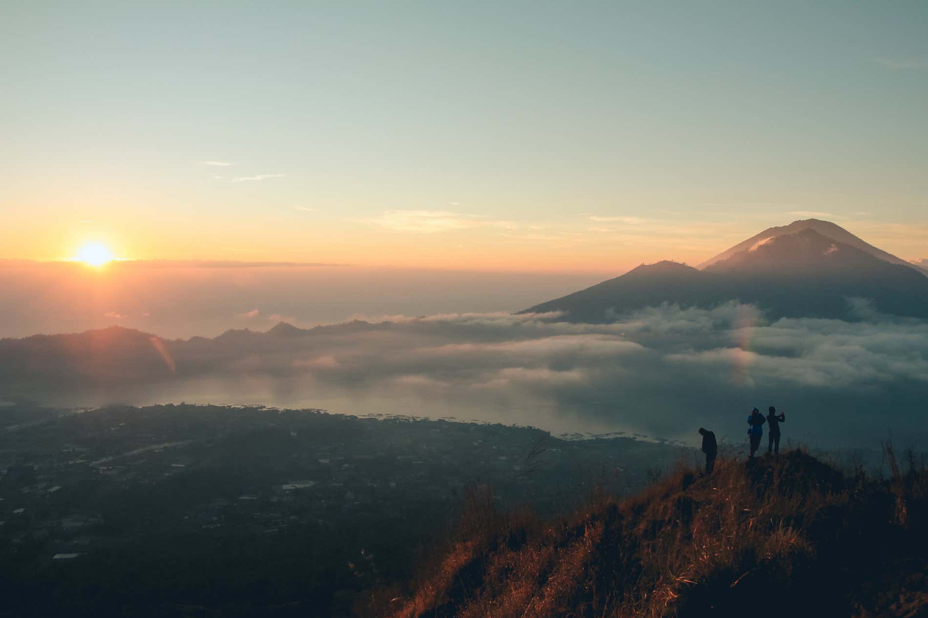 Il sole che sorge all'orizzonte, con il monte Batur visibile sulla destra.