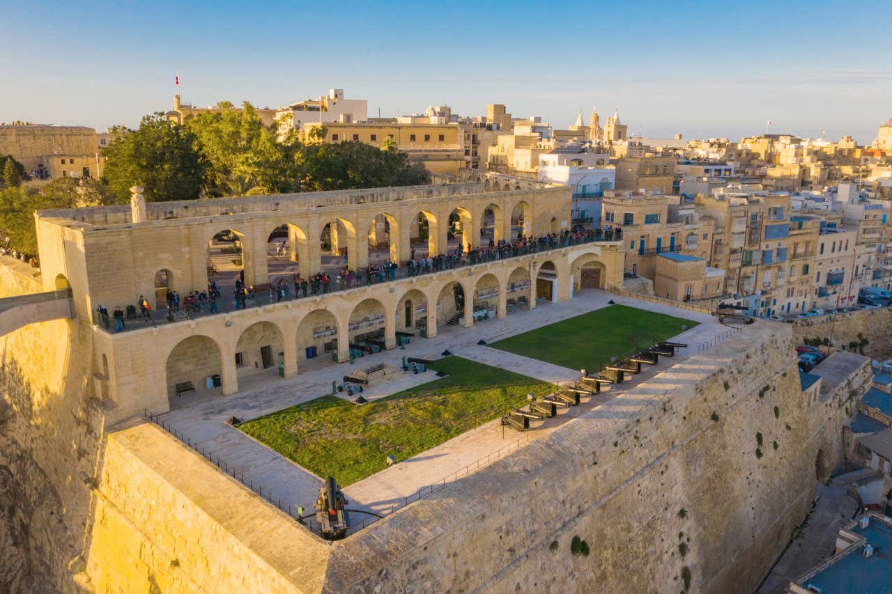 The high gardens of Barrakka at sunset with a stone terrace and a row of cannons.