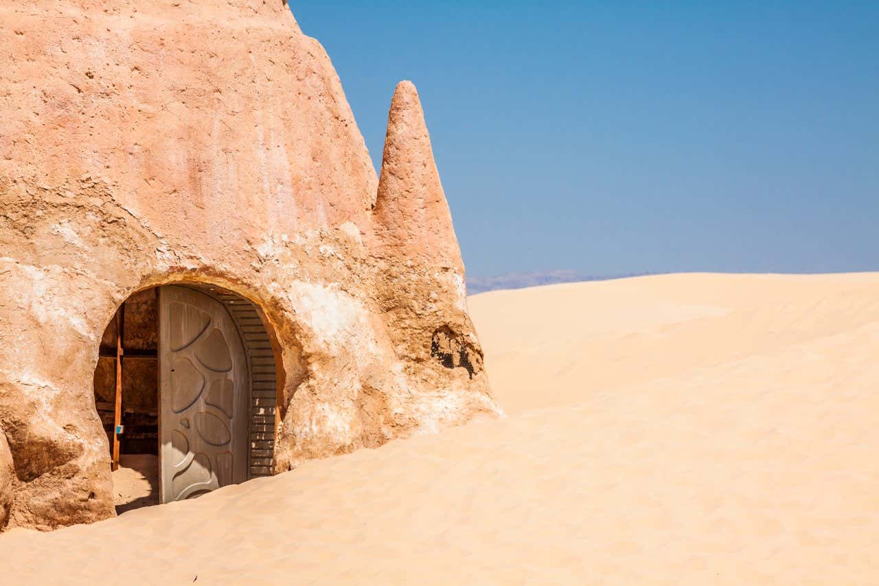 Una costruzione in argilla a forma di cupola con una porta metallica immerso nella sabbia gialla del deserto della Tunisia