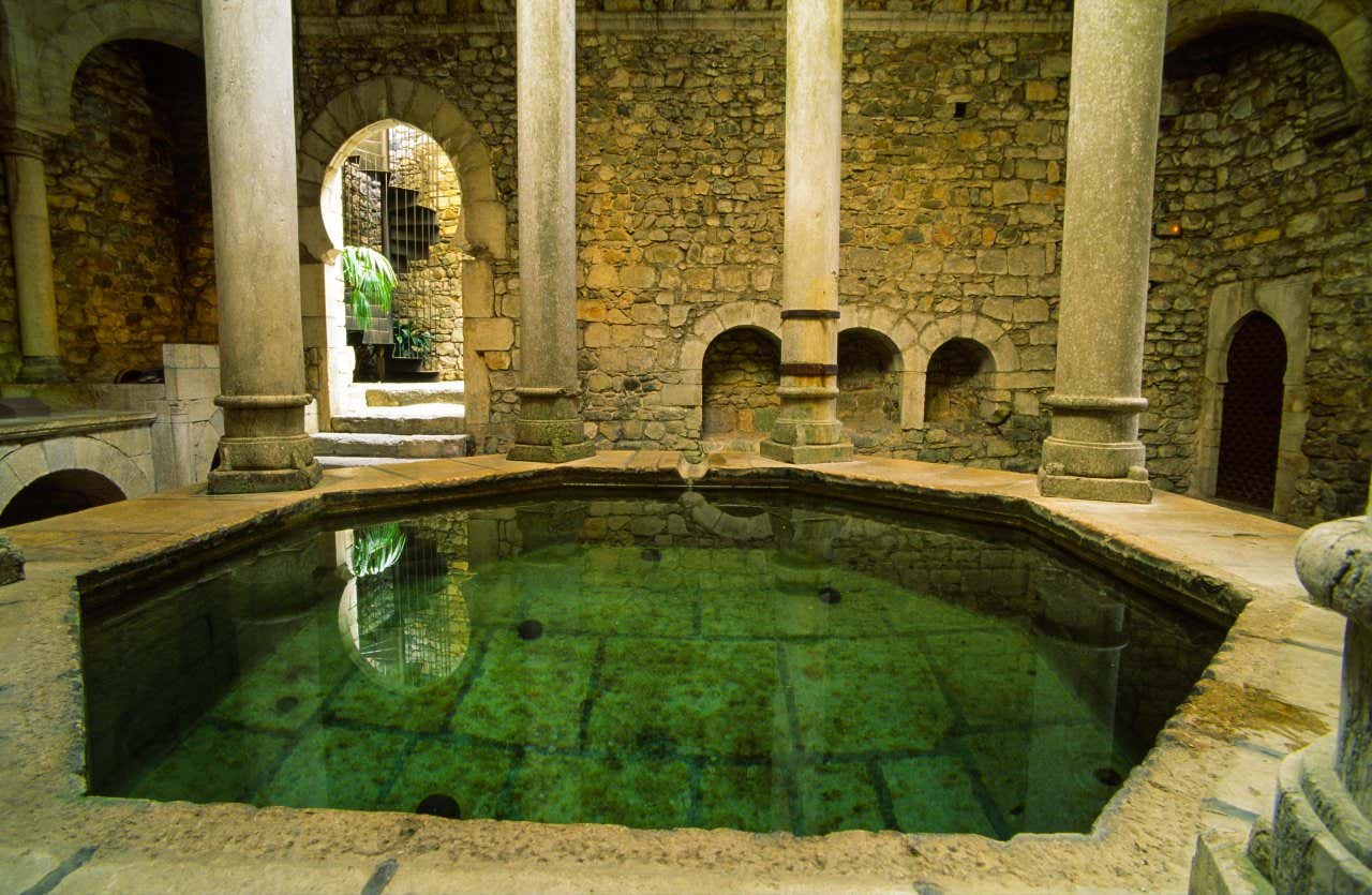 Un chiostro coperto con al centro una piccola piscina in pietra circondata da colonne