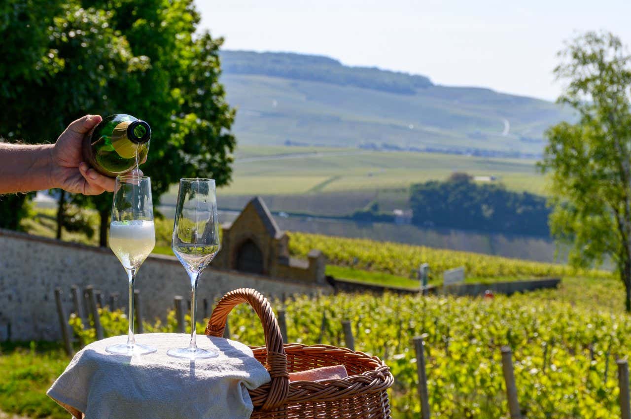 Un homme servant du champagne dans des flûtes dans un vignoble sur la Route touristique du champagne