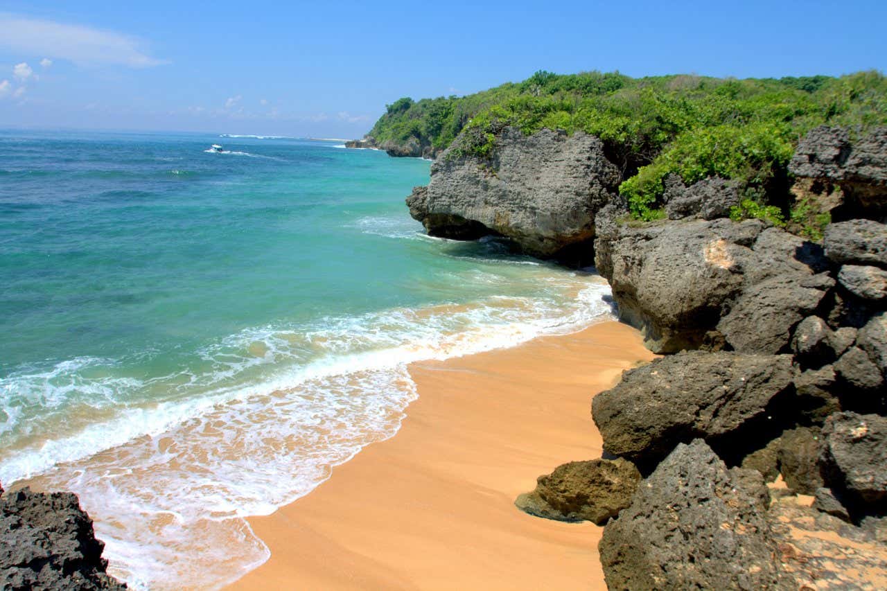 Una playa en la costa de Nusa Dua en Bali, con un cielo azul claro de fondo y rocas en primer plano