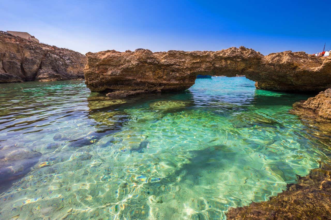 Arc-shaped rocks resting on the crystal-clear water of the sea of Comino, Malta.