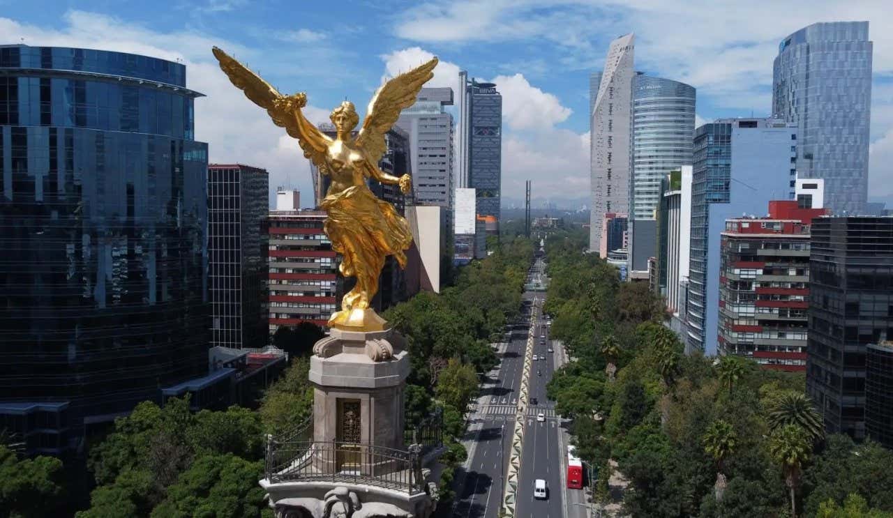 Escultura do Ángel de la Independencia à frente de diversos edifícios modernos