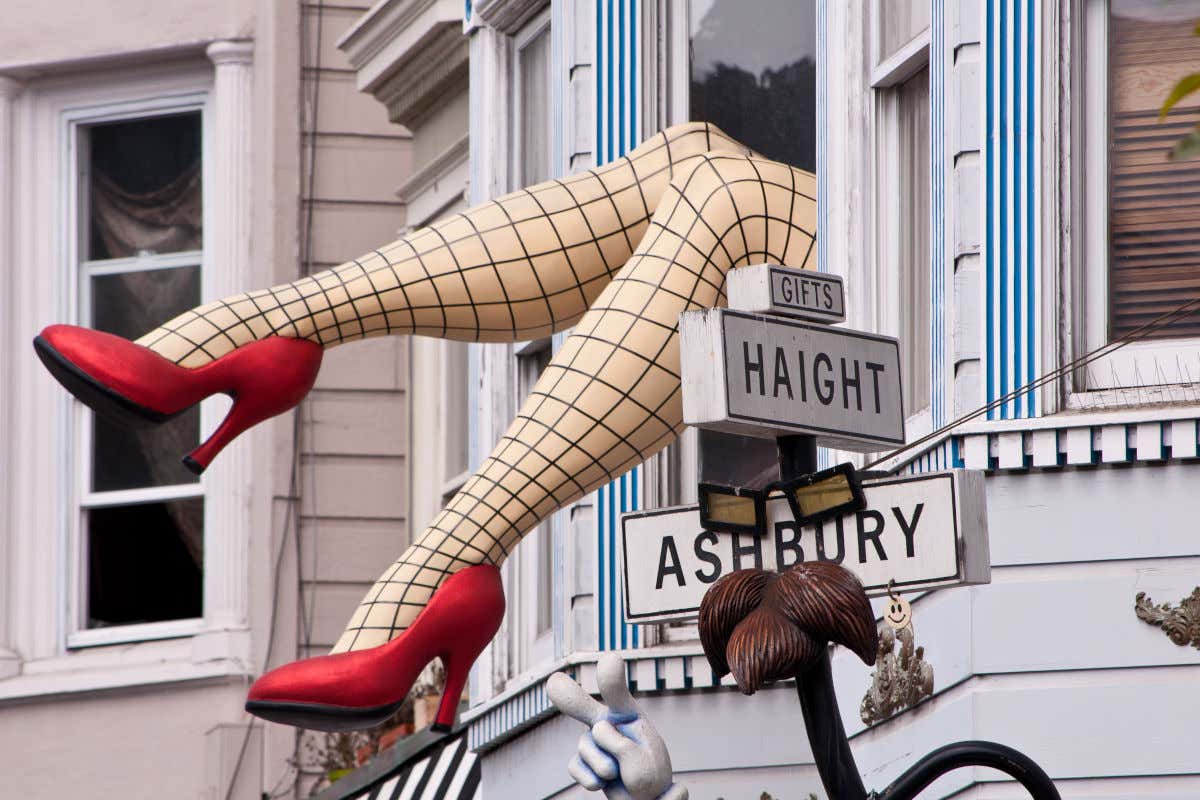 Legs of a sculpture in fishnet stockings and high heels sticking out of a window in the Haight-Ashbury neighborhood.