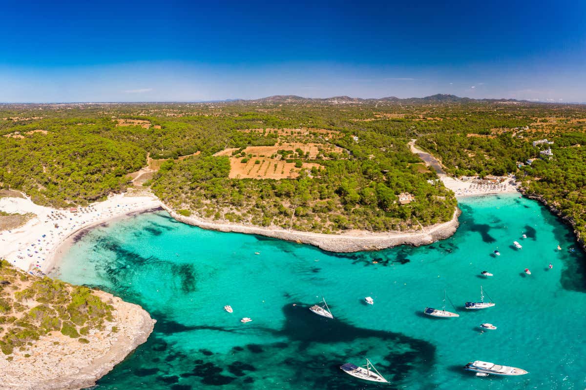 Vista aérea del Parque Natural de Mondragó, un paraje costero de aguas cristalinas con varias calas de arena, barcos y vegetación alrededor