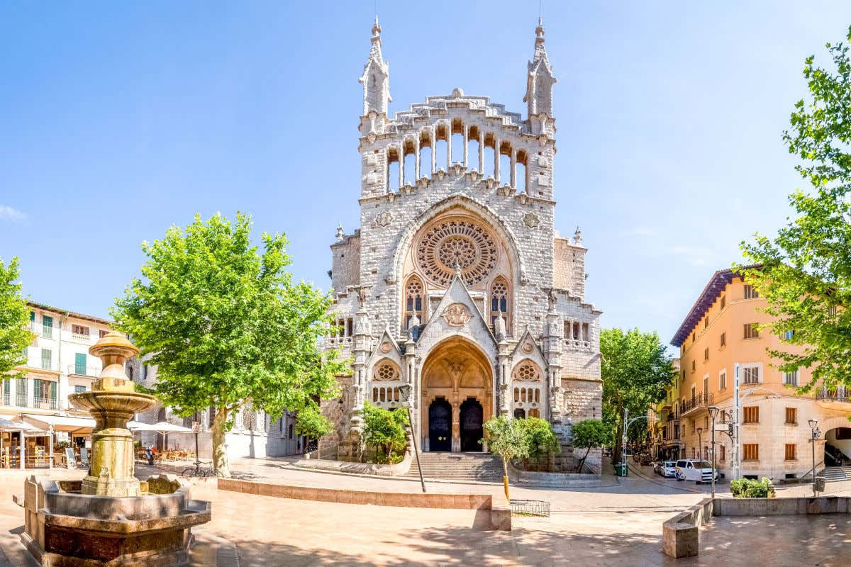 Iglesia de San Bartolomé en una plaza con una fuente de piedra y rodeada de edificios residenciales