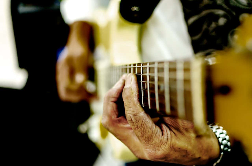 Primo piano sulle mani di un uomo che suona la chitarra elettrica