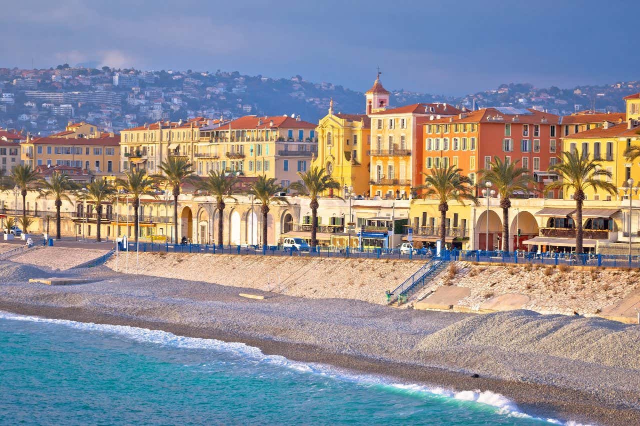 Vista da praia de Nice com o Promenade del Anglais e edifícios coloridos ao fundo