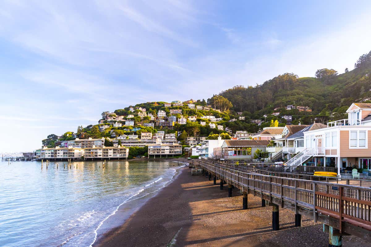 Several houses on a hill near the beach with a small wooden boardwalk in Sausalito.