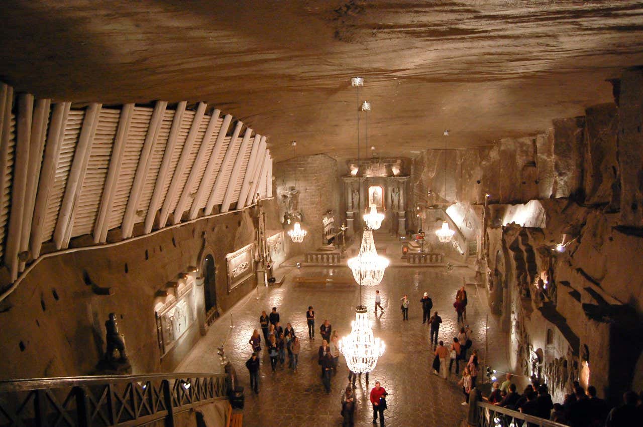 A large hall within the Wieliczka Salt Mine, with lots of people inside.