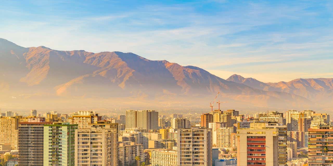 Vue panoramique sur la ville de Santiago avec des montagnes en fond sous un ciel bleu et quelque peu nuageux