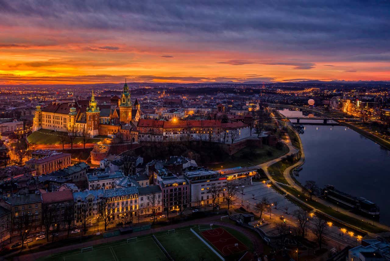 An aerial view of Wawel Hill at night with the river running along the right of the image.