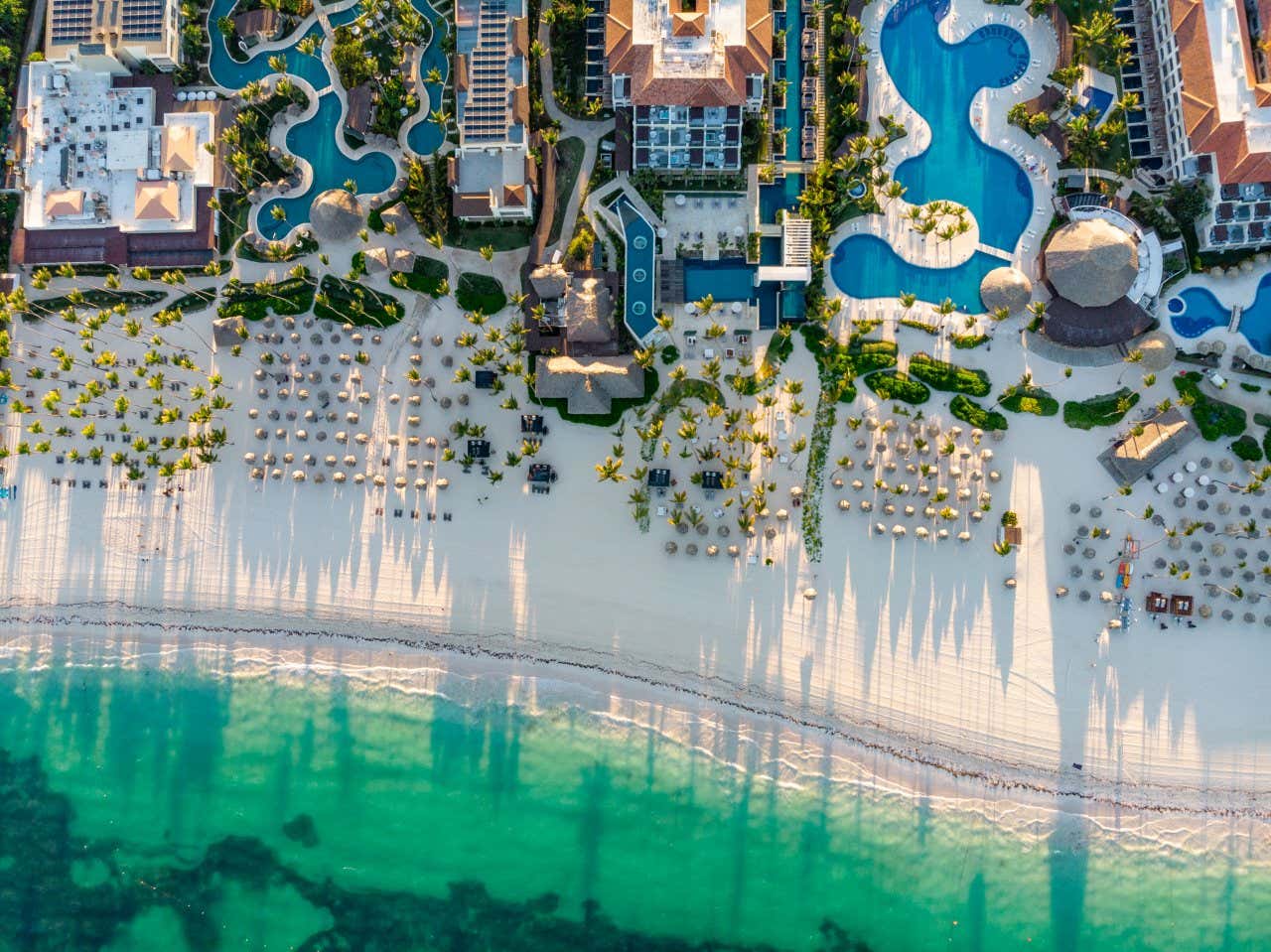 Aerial view of Punta Cana with hotel resorts with pools and the beach with palm trees