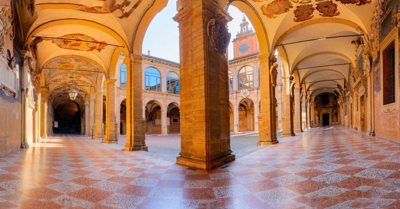 Un cortile interno di un antico palazzo medievale circondato da logge finemente decorate con affreschi