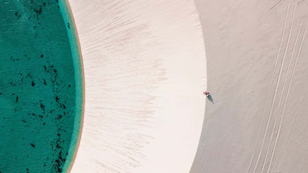 Vue aérienne d'eau émeraude au bord d'une dune de sable blanc