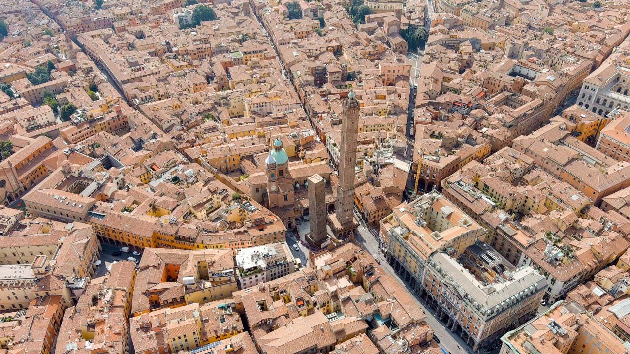 Il centro storico di Bologna fotografato dall'alto in un giorno di sole, con due torri medievali erette al centro di una piccola piazza