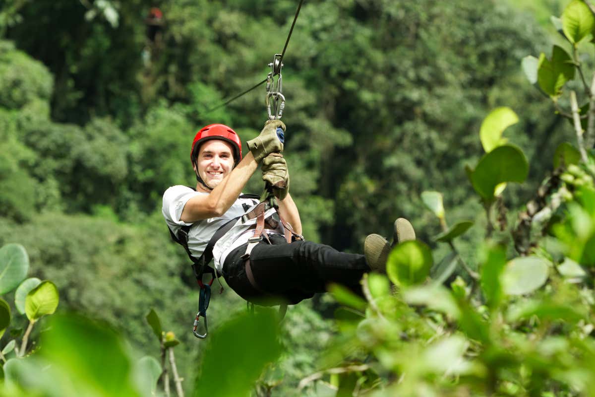 Un hombre se desliza en tirolina entre la jungla