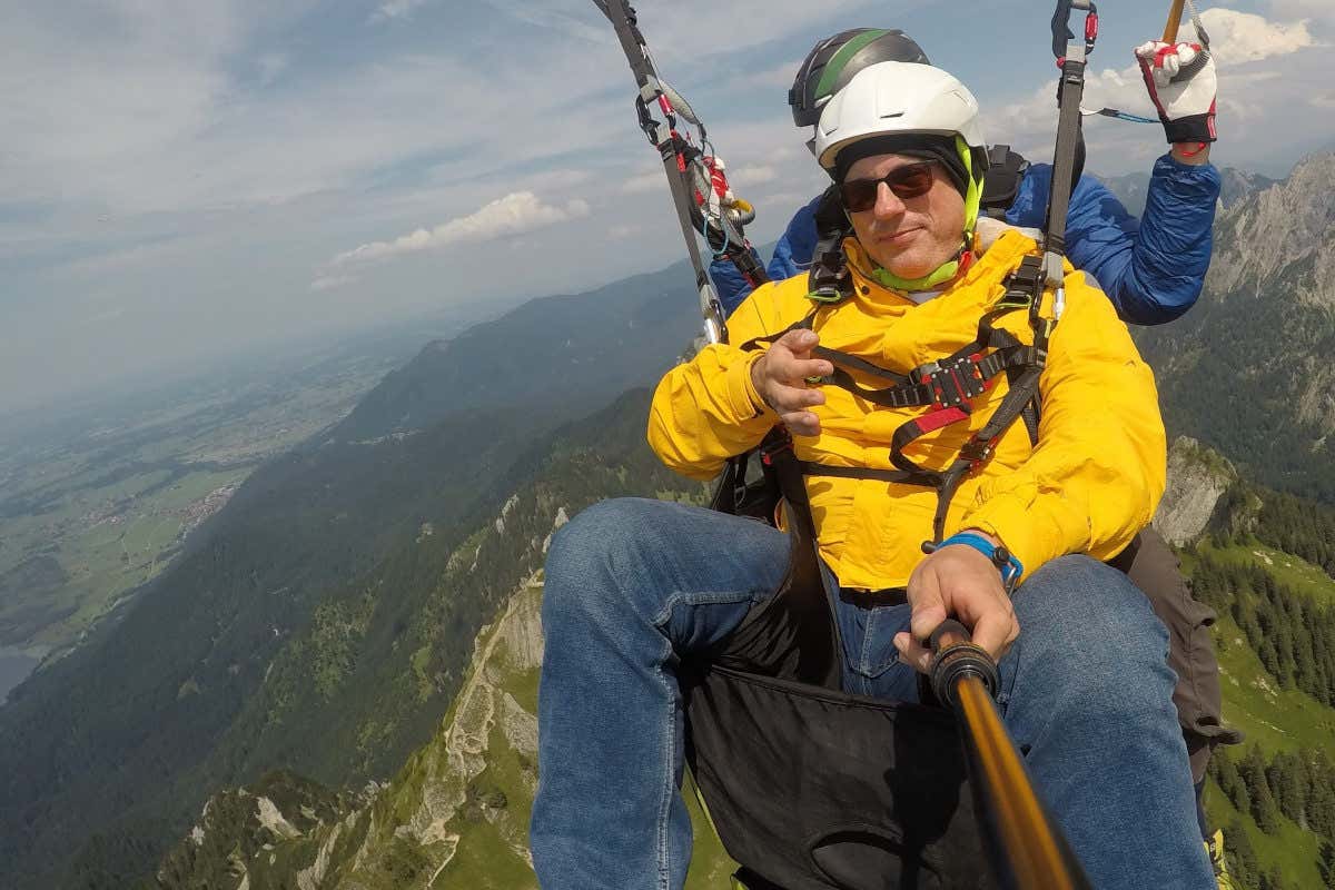 Dos hombres volando en parapente sobre un verde paraje