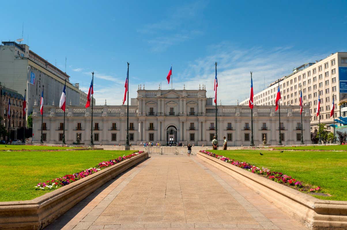 Fachada del Palacio Presidencial, en frente banderas de chile y los jardines 