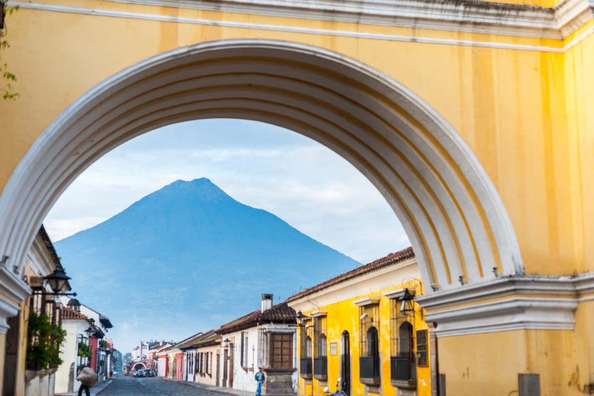 Casas de colores vistas bajo un arco amarillo con un volcán al fondo