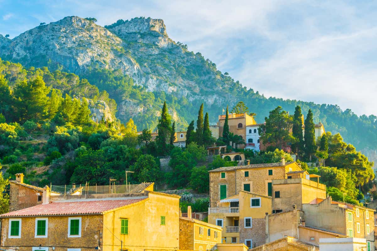 Casas rurales del pueblo de Estellencs en las faldas de una montaña de Mallorca rodeadas de árboles