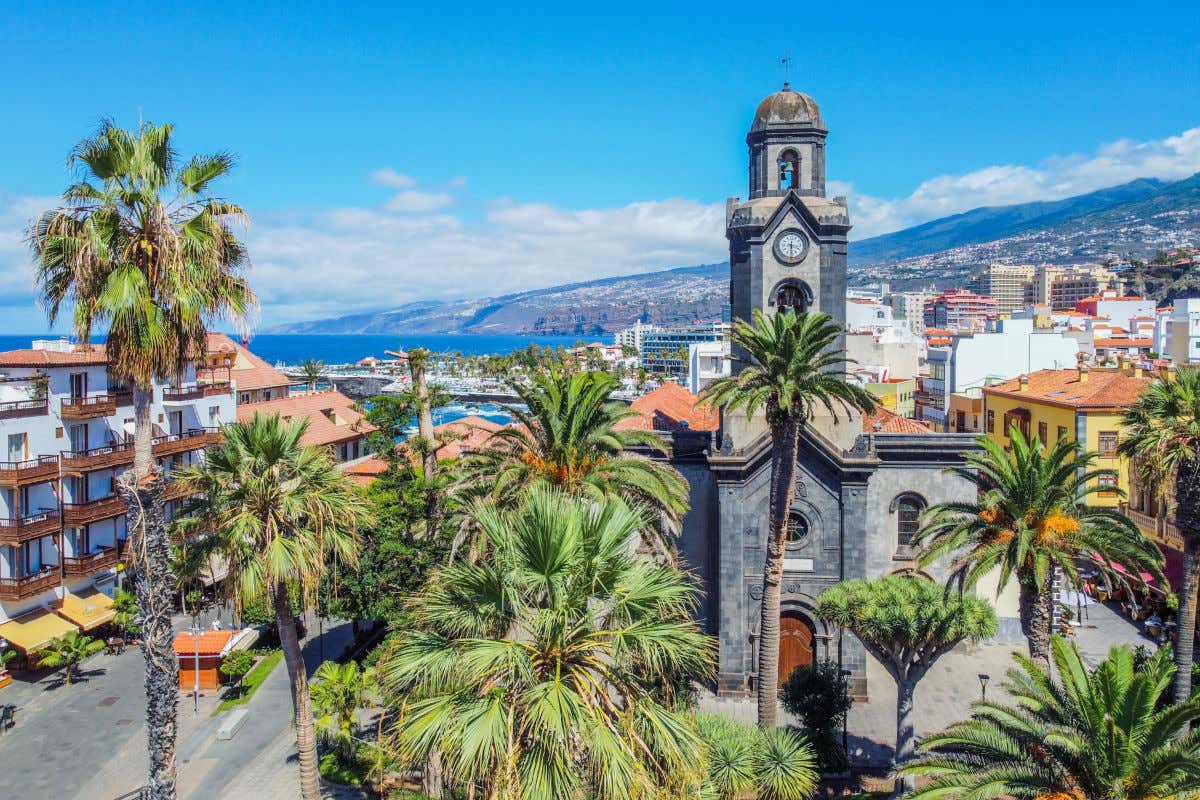 Aerial view of a stone church in Puerto de la Cruz with several buildings and mountains behind.
