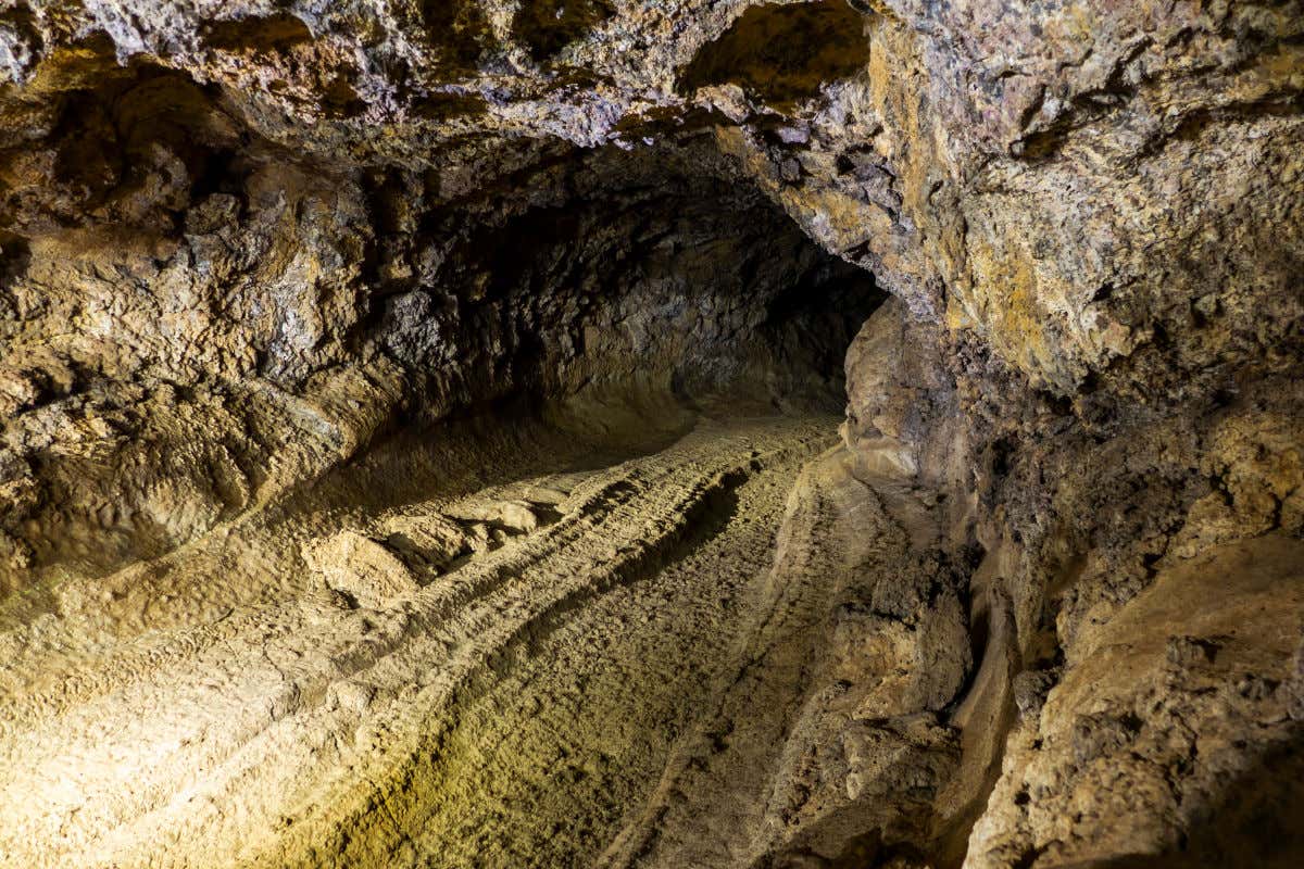 Interior of a volcanic cave, a dark passage surrounded by solidified lava.