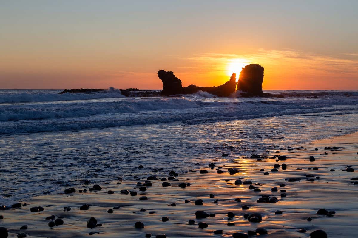 Atardecer entre grandes rocas en la playa El Tunco