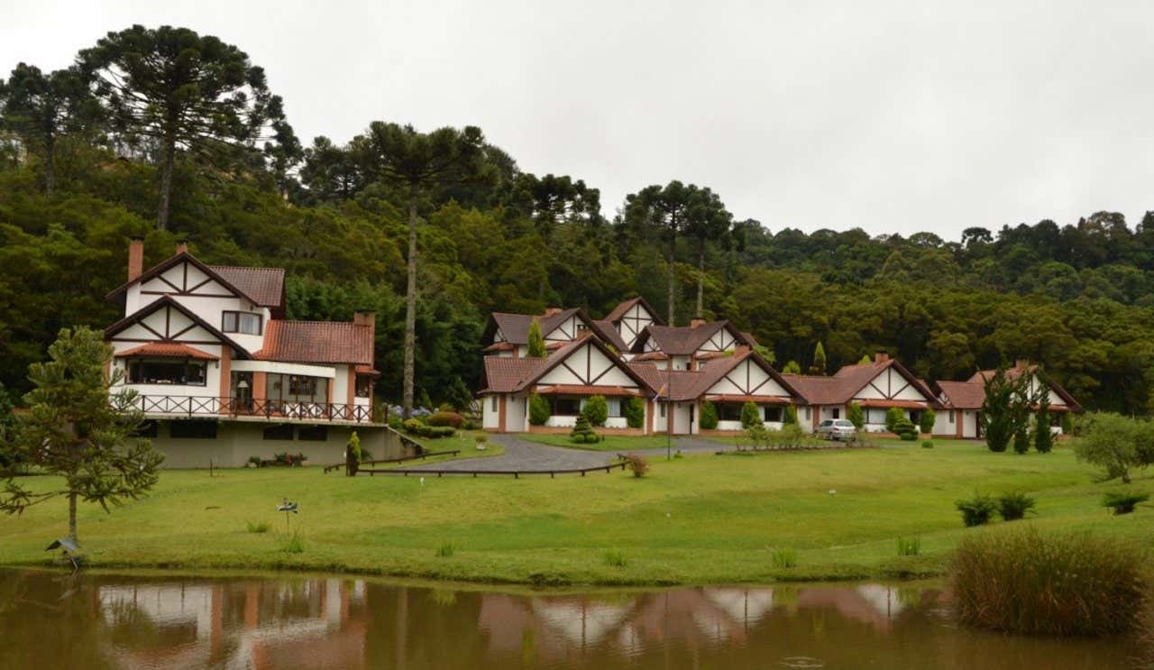 Diversas casas em estilo alpino rodeadas de vegetação em frente a um lago