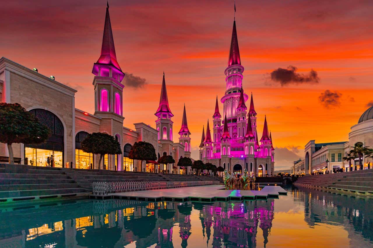 The Land of Legends amusement park in Belek, with a castle in the foreground and an oragne sky in the background.