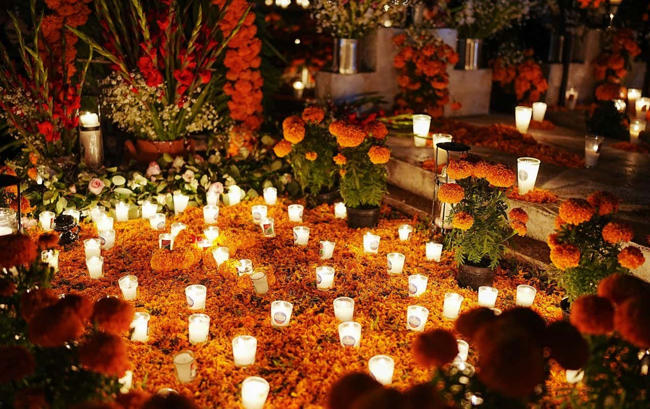 Túmulos de entes queridos decorados com flores laranjas e vejas para a celebração do Dia dos Mortos