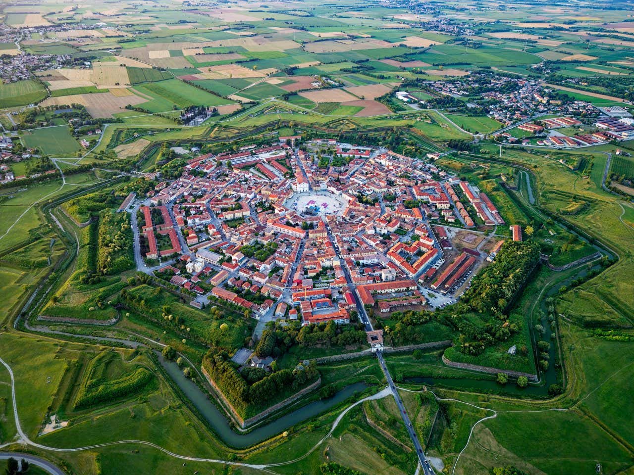 Vista aerea di un centro abitato ordinato da strade convergenti in una piazza centrale. Il perimetro del borgo è inoltre circondato da mura a forma di stella a nove punte, intorno si vede un'estesa campagna pianeggiante