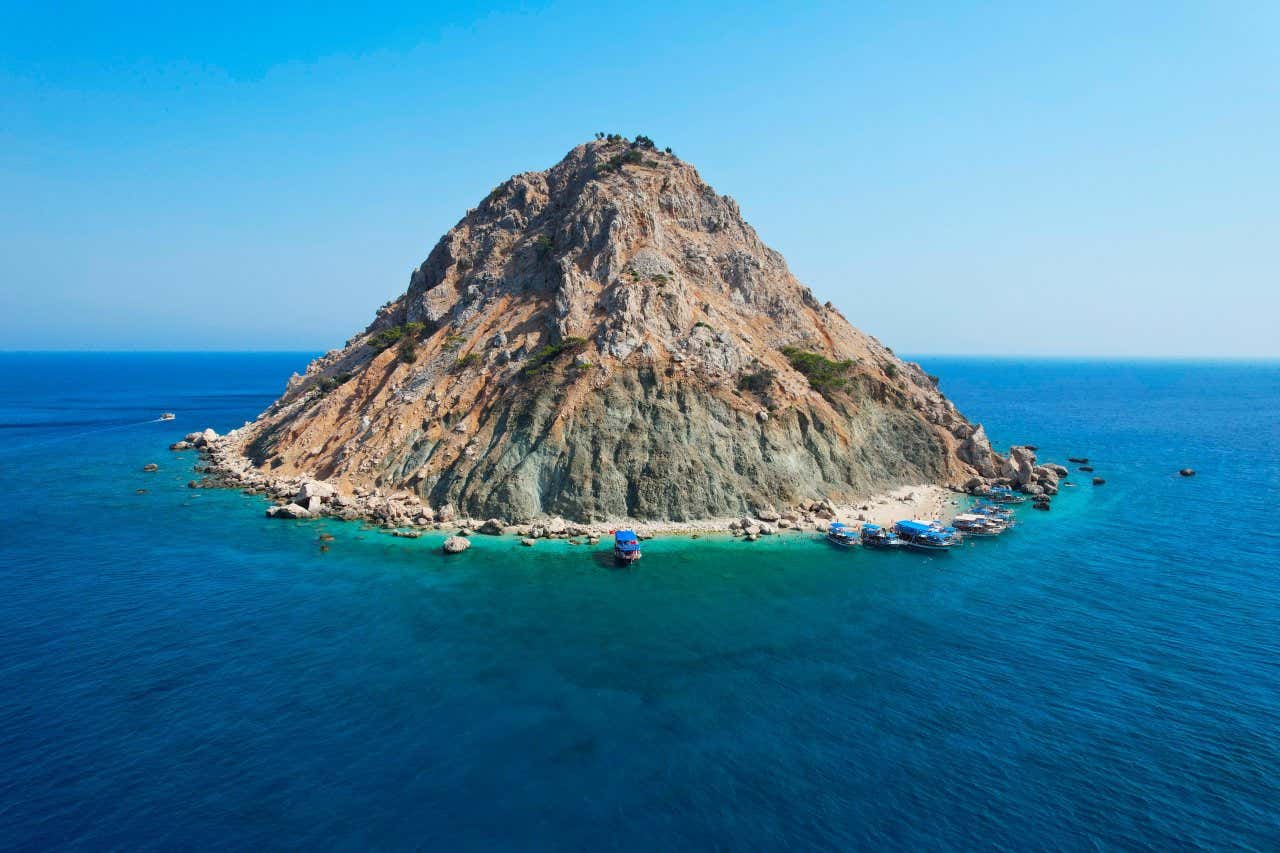 Suluada Island as seen from off shore with boats docked at the shore.