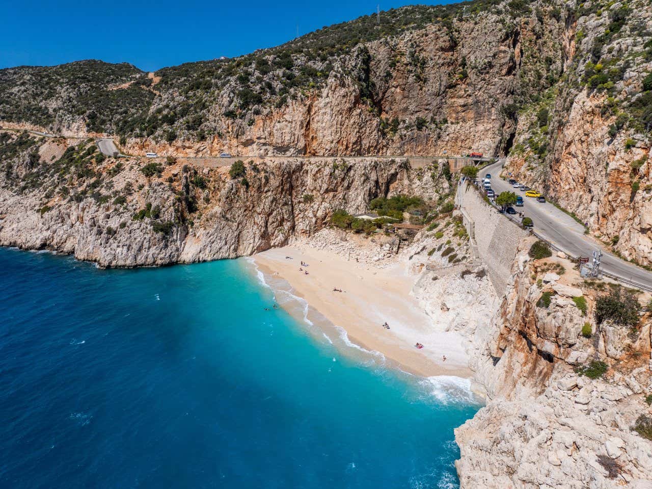 An aerial view of the Kaputas Beach, with a road visible on the cliffs above.