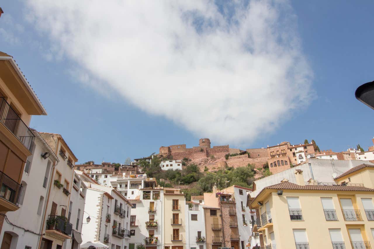 Casas agrupadas en Villafamés con el cielo azul y una nube coronando