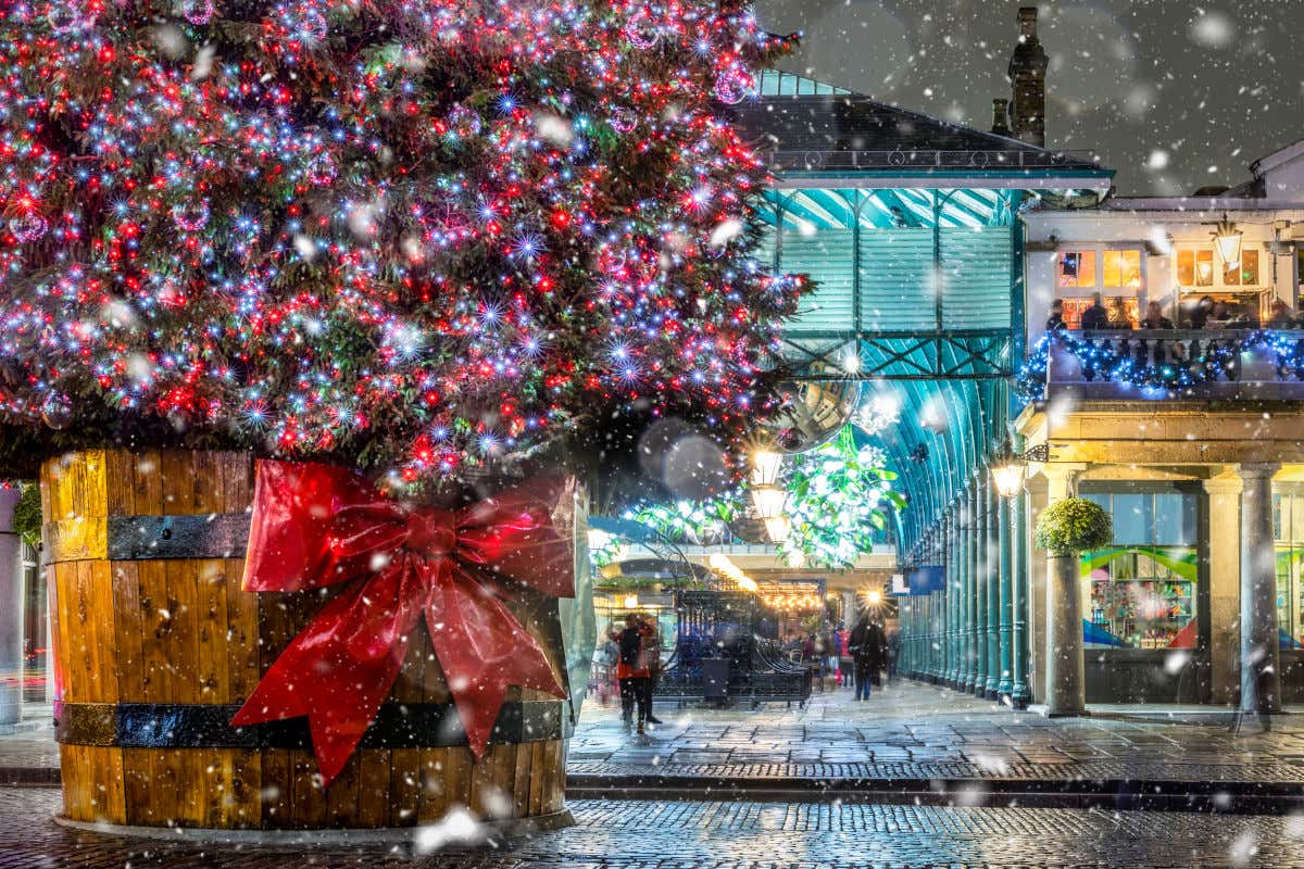 Una gigantesca maceta con un lazo rojo conteniendo un gran árbol de Navidad en Londres frente a un mercado cubierto