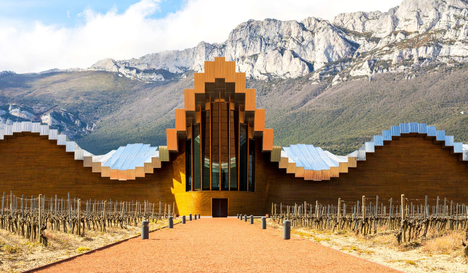 Fachada de una bodega vanguardista de la Rioja Alavesa con unas montañas de fondo