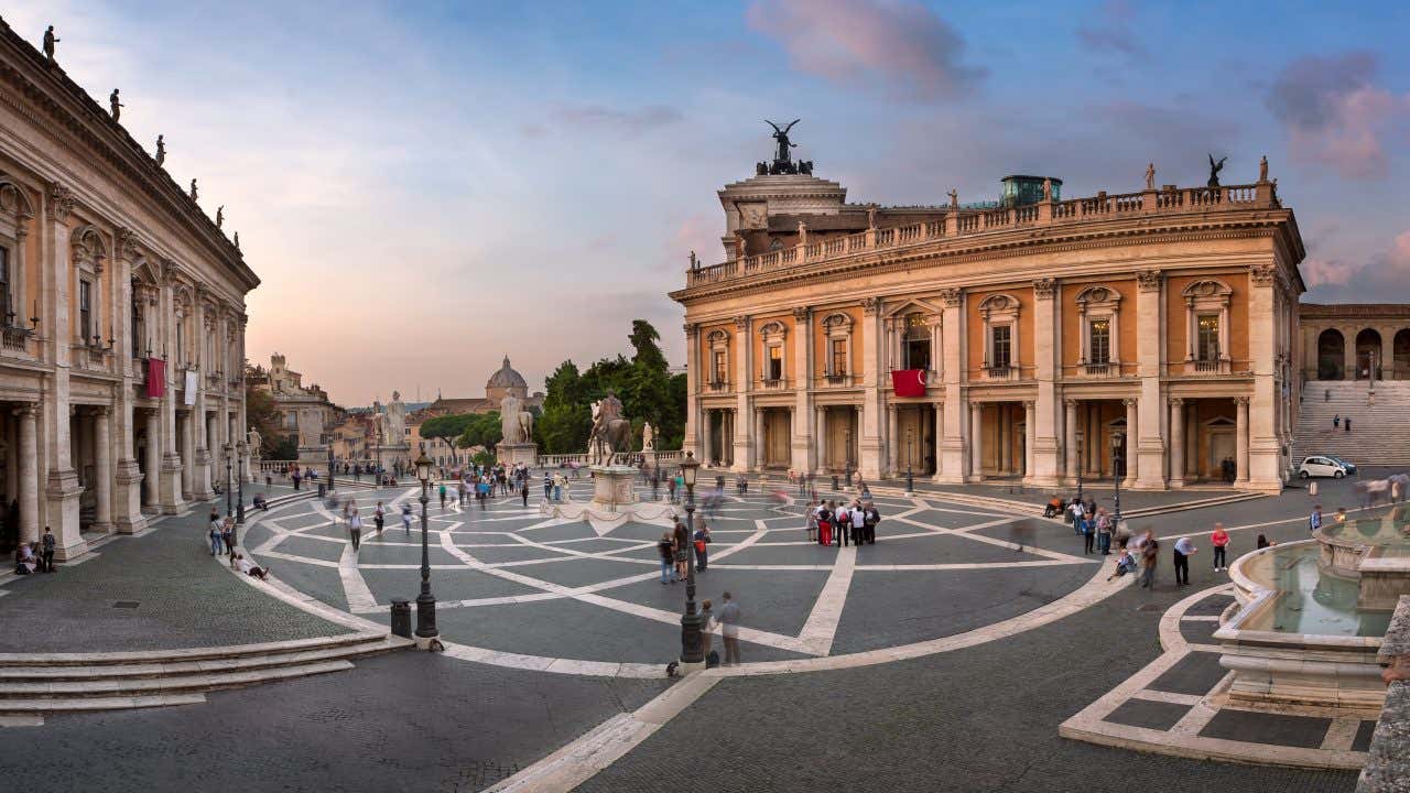 A view of Piazza del Campidoglio with tourists walking around under a cloudy sky.