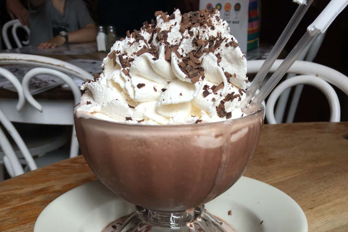 Una copa de chocolate con nata por encima en la mesa de un restaurante