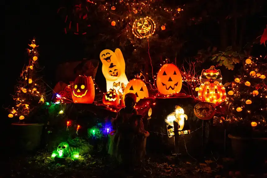 Décorations d'Halloween en forme de citrouilles, de squelettes et de fantômes illuminées à côté d'un arbre