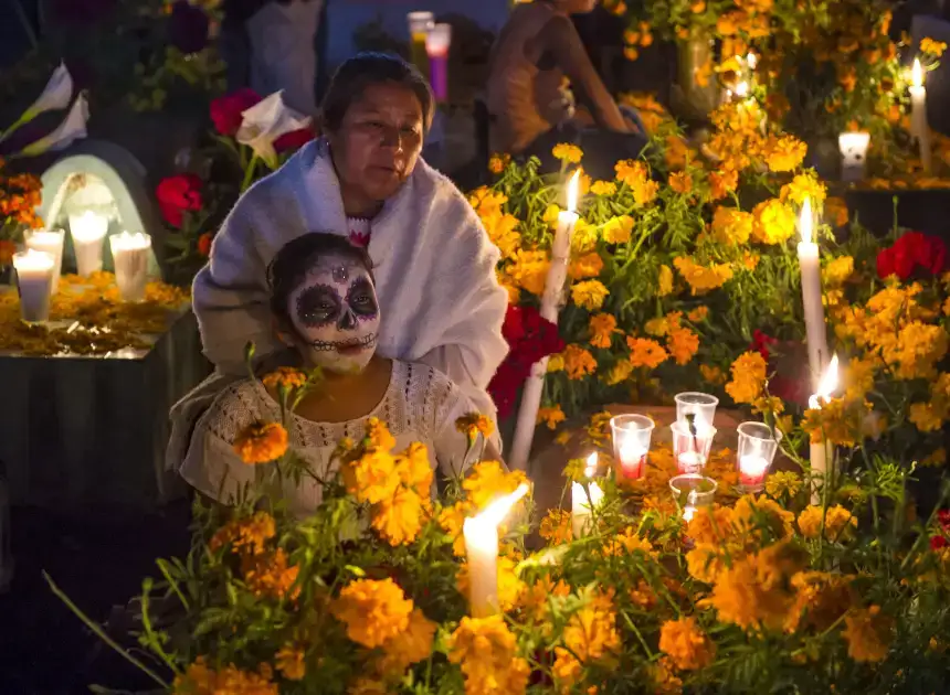 Des femmes entourées de bougies et de fleurs à l'occasion du Día de Muertos au Mexique