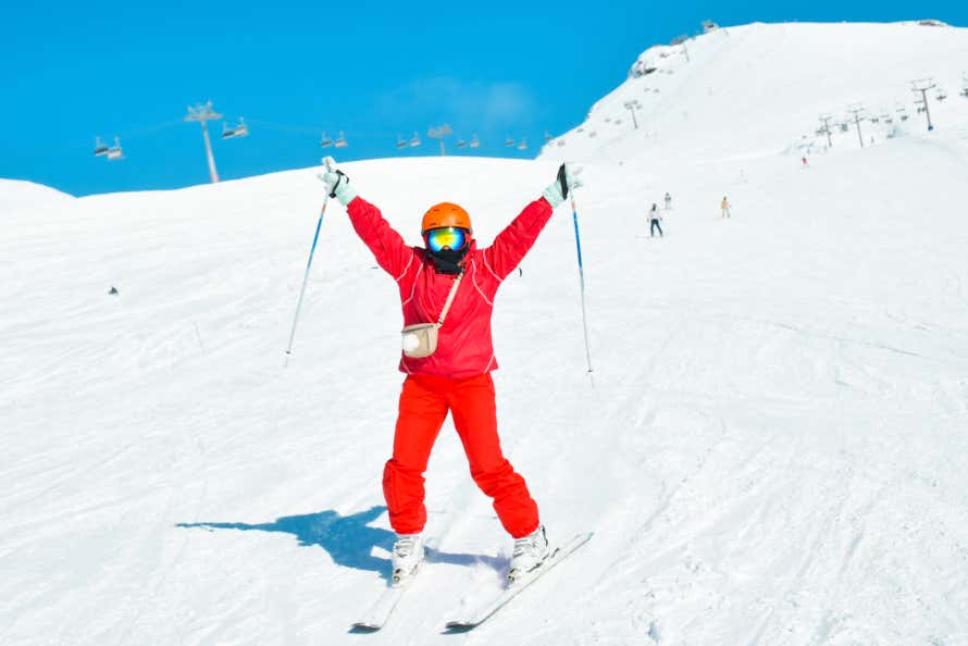 Un hombre vestido con un mono de color rojo esquiando en las pistas de nieve de una estación de esquí