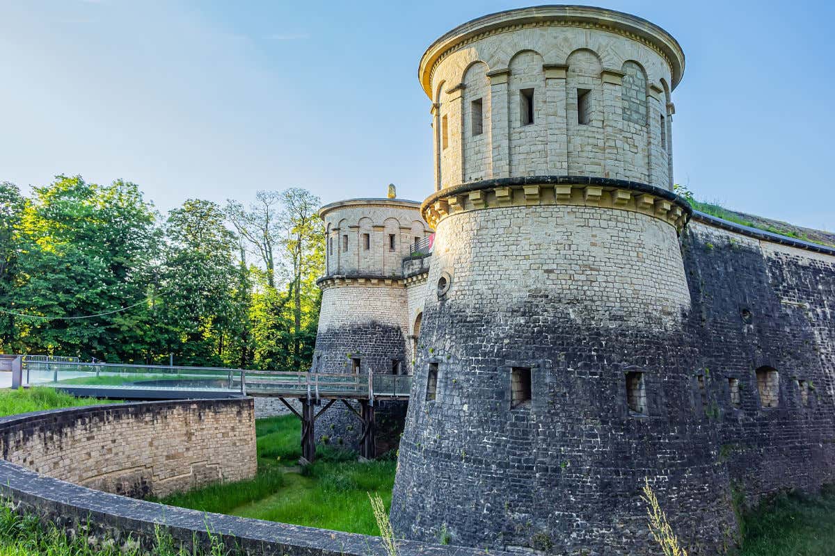 Fort Thüngen, uma fortaleza com duas torres altas e uma ponte levadiça sobre um fosso com gramado
