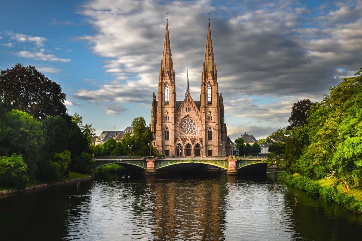 Panorámica de la iglesia de San Pablo con sus dos altas torres frente a un puente y un río