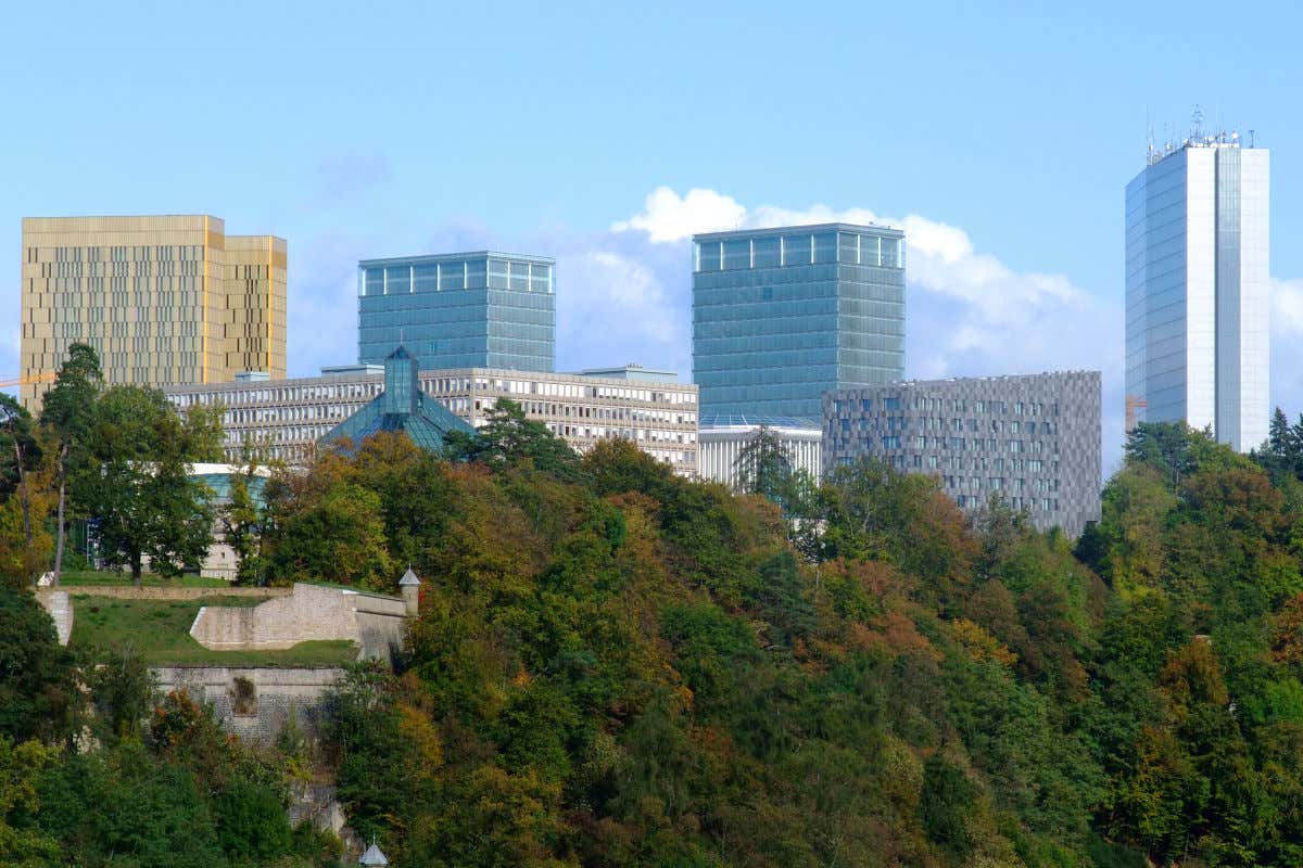 Vários edifícios altos e de aparência moderna em uma colina com vegetação abundante
