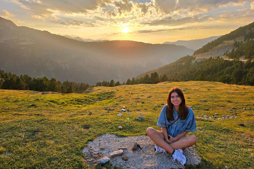 Lucía Fernández sentada en un prado al atardecer, con las montañas de fondo