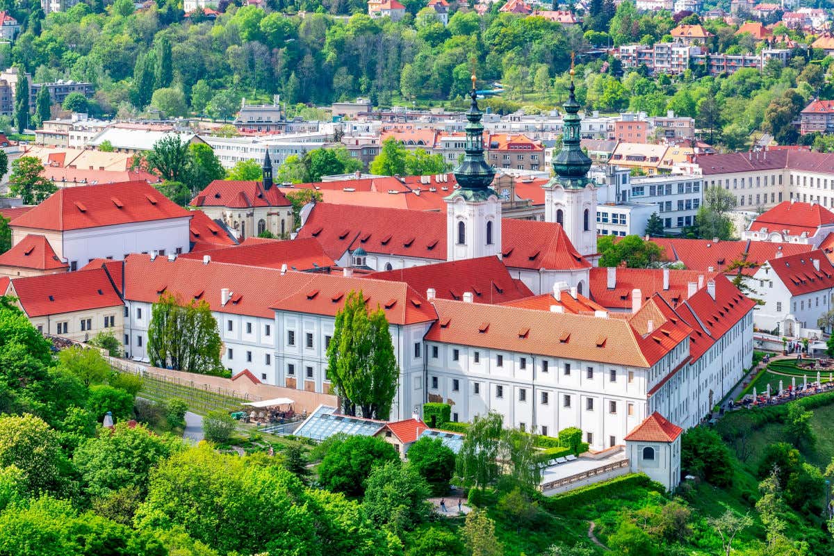 Vista aérea do Mosteiro Strahov em Praga, um edifício branco com telhados avermelhados cercado por vegetação