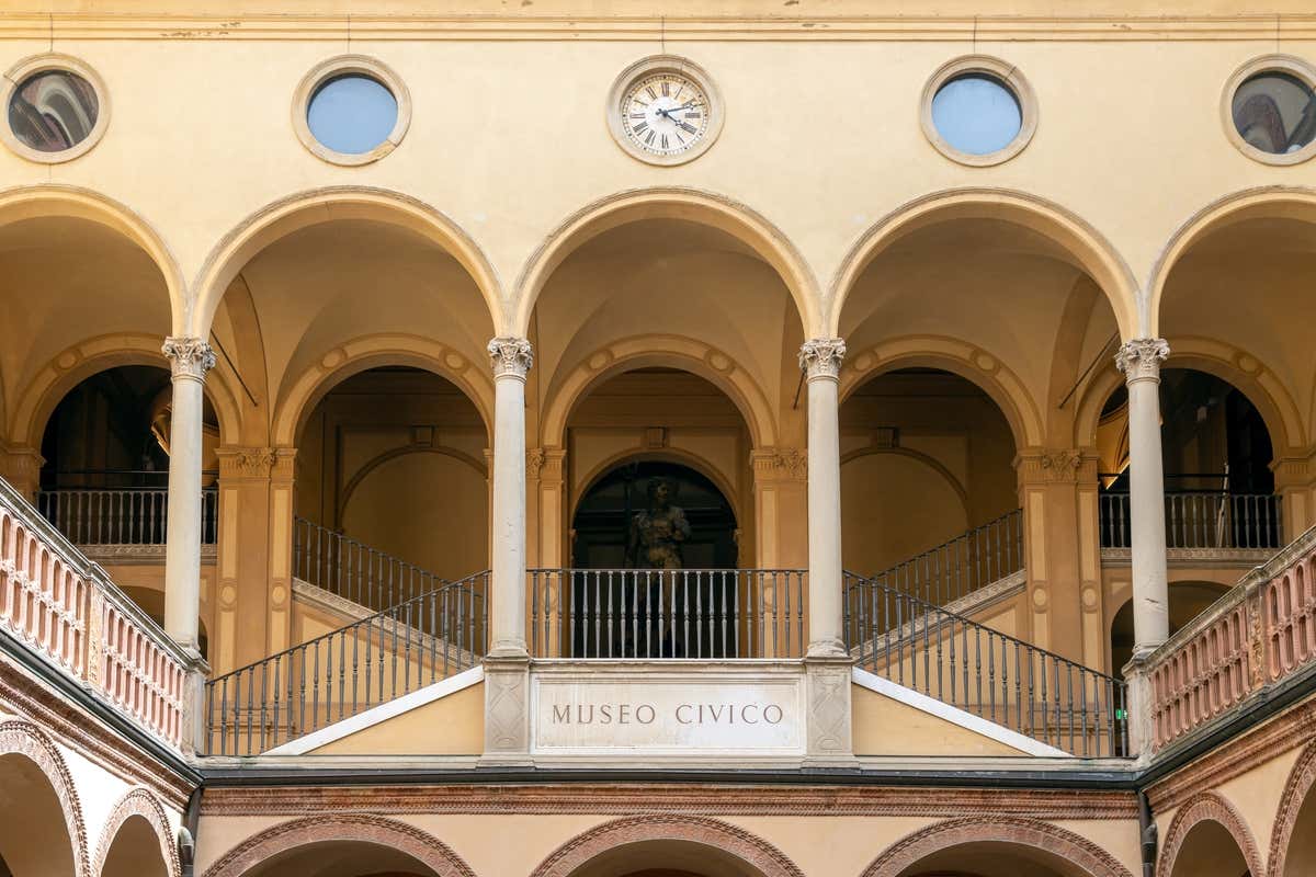 Patio interior del museo cívico Arqueológico de Bolonia, con una estatua en el centro de cuatro arcos de piedra