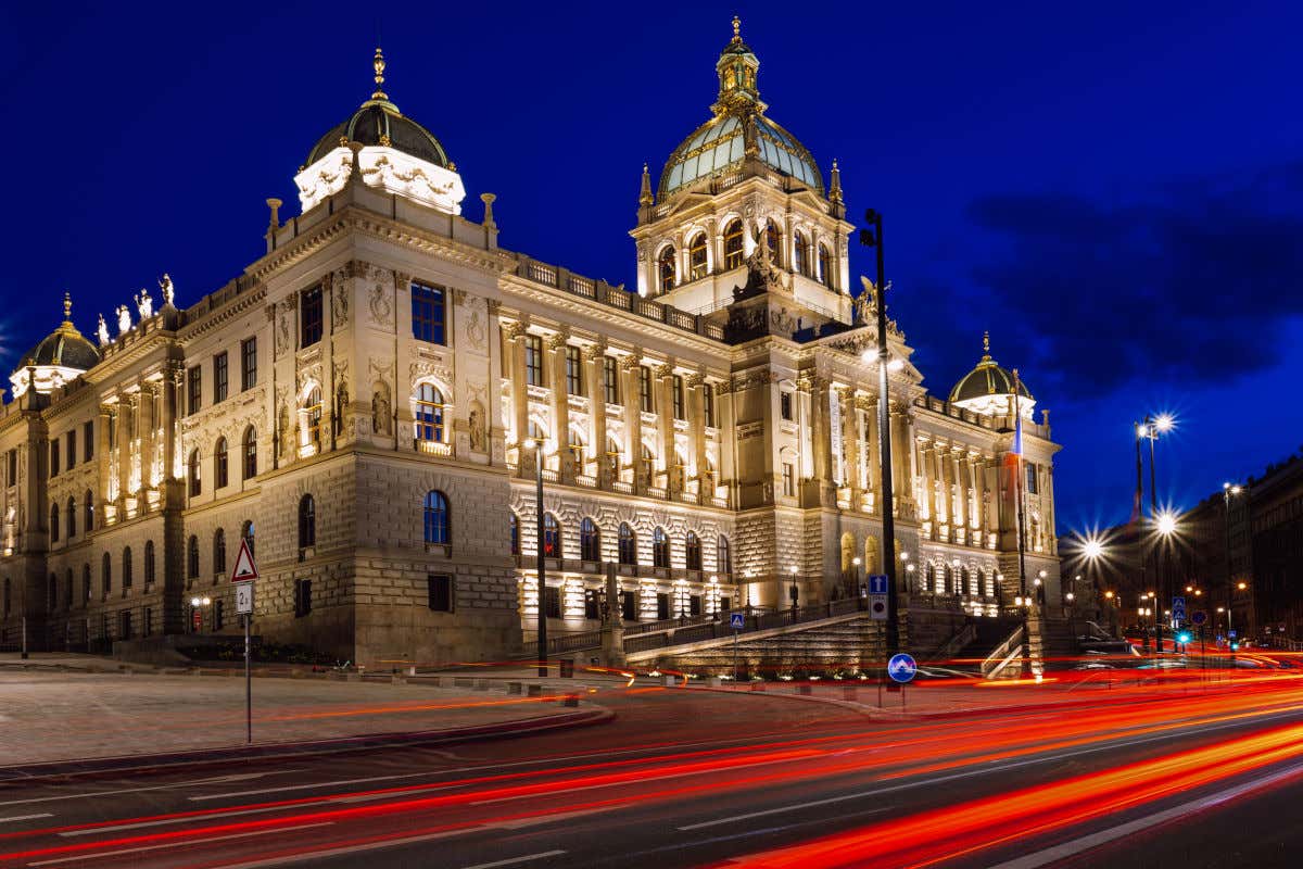 Vista noturna da fachada do Museu Nacional de Praga, um edifício coroado com várias cúpulas